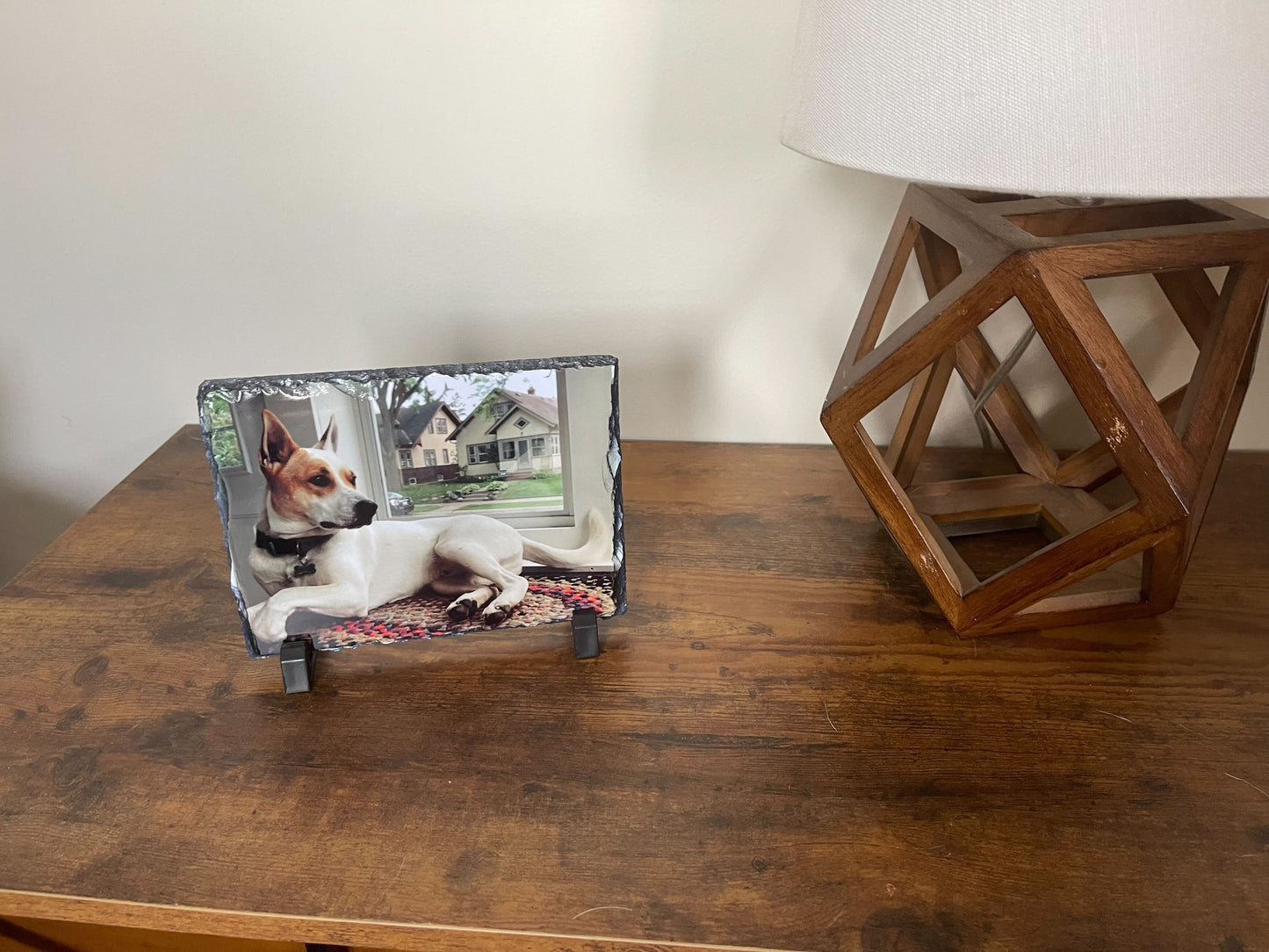 sublimated photo frame featuring a dog facing the right near a window. the photo frame is placed on a table with a home decor beside it